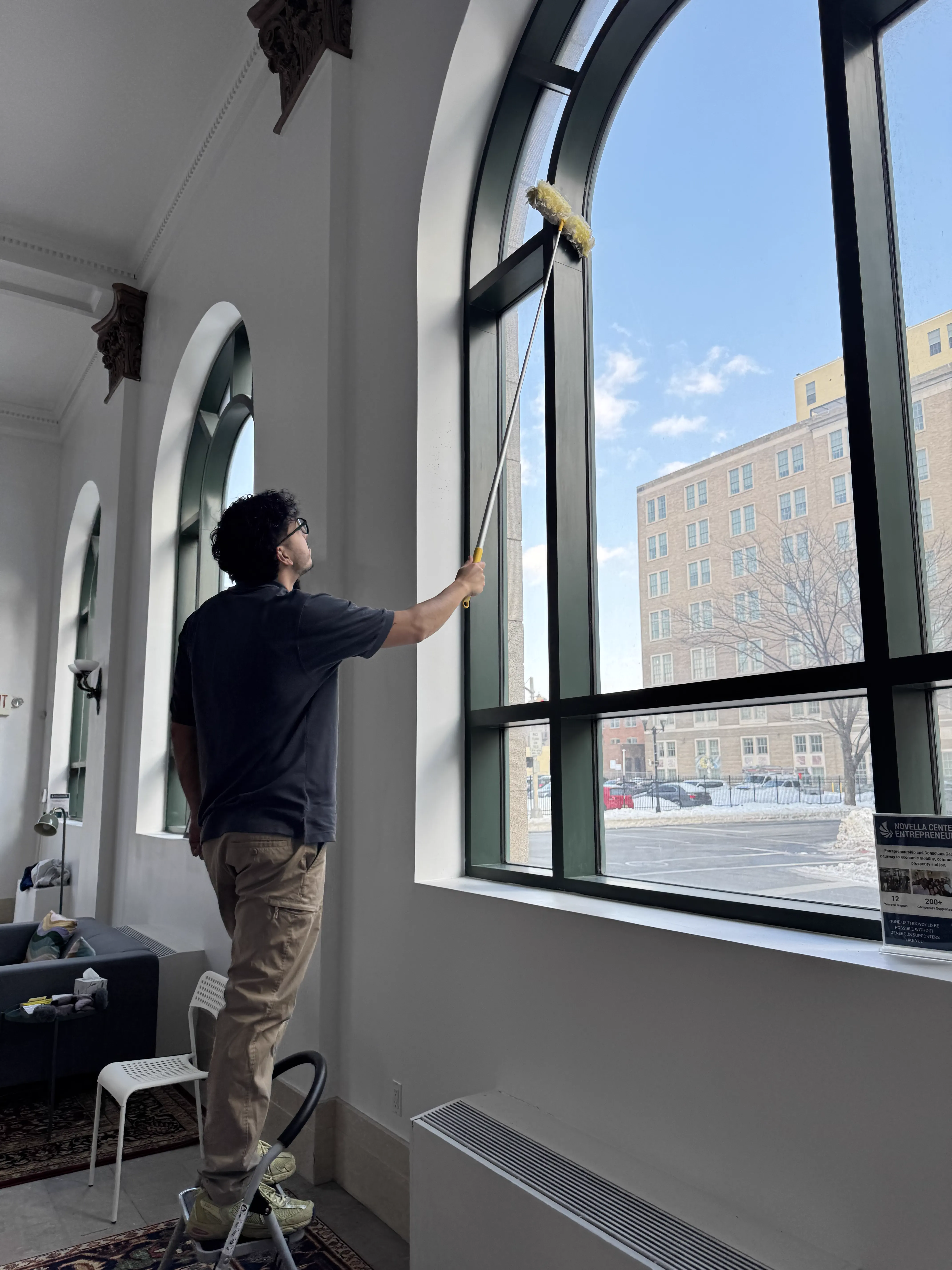 Alexander Morales limpiando ventanas altas con herramientas de extensión