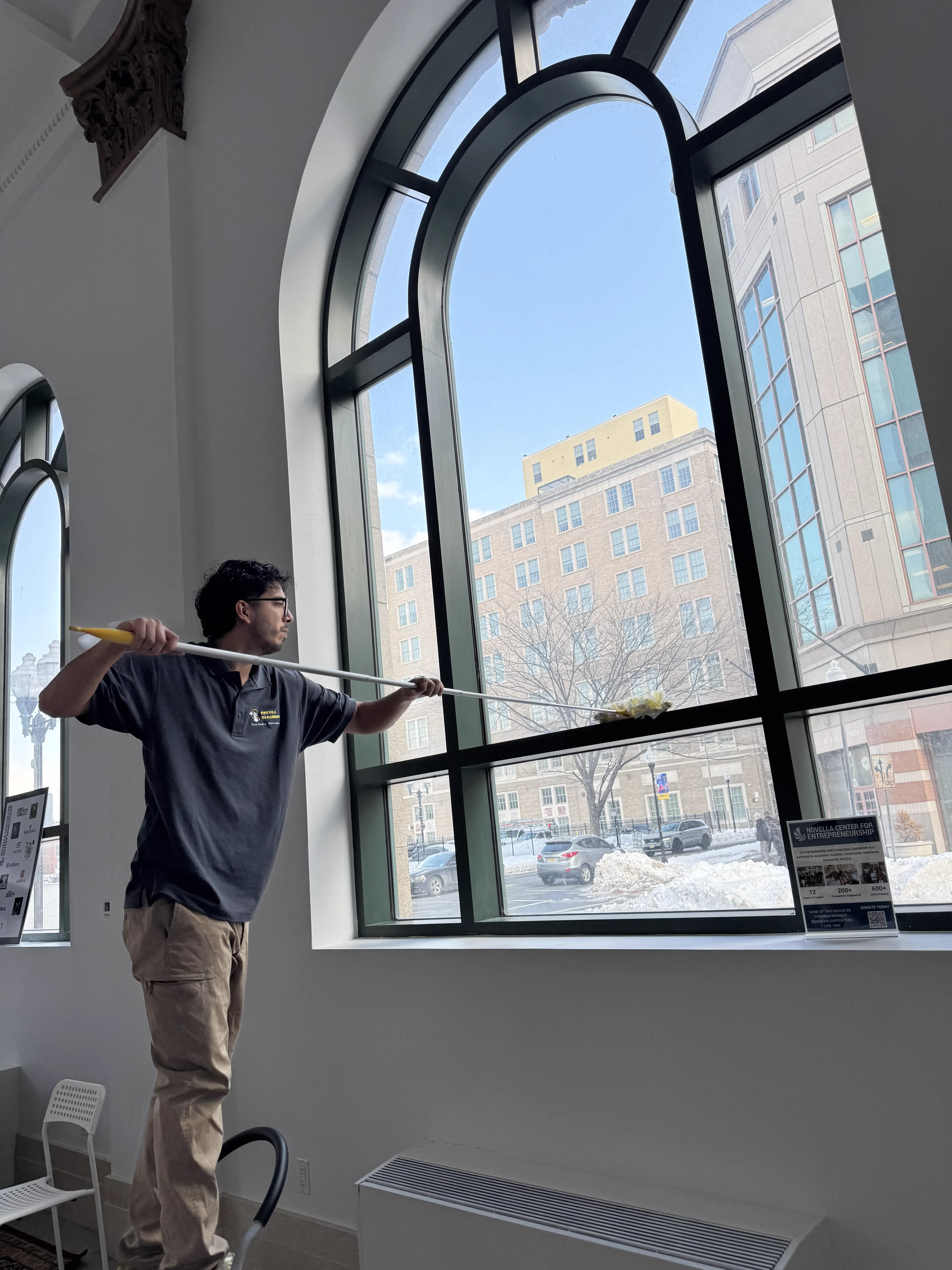 Alexander Morales, founder of Fresca Cleaners, cleaning a large interior window